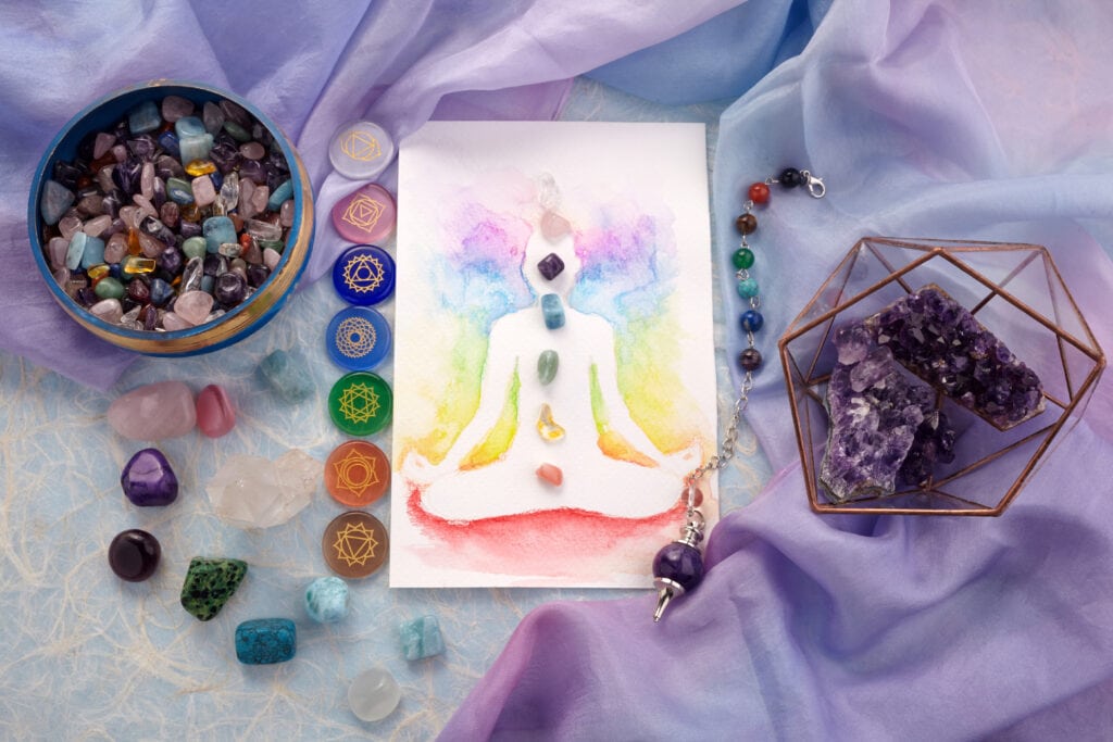 Natural crystals and pendulum on pastel silk background. Reiki background with card. Top view